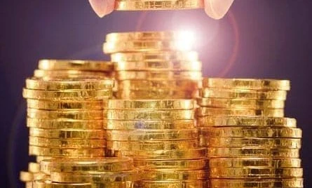 Close-up of shiny gold coins symbolizing wealth and saving money. Hand holding a stack of cash, representing financial security and currency handling.