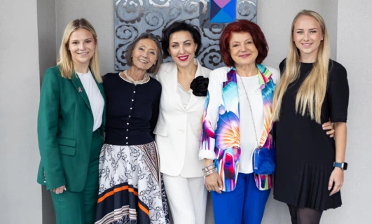 Kobieta z uśmiechem na twarzy, ubrana w stylowy bezrękawnik z tekstyliów. Promieniuje szczęściem na wydarzeniu modowym.