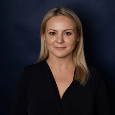 A smiling woman with perfectly groomed eyebrows and lips, glowing skin, and a radiant smile. Her beauty shines through in her joyful facial expression and relaxed posture.