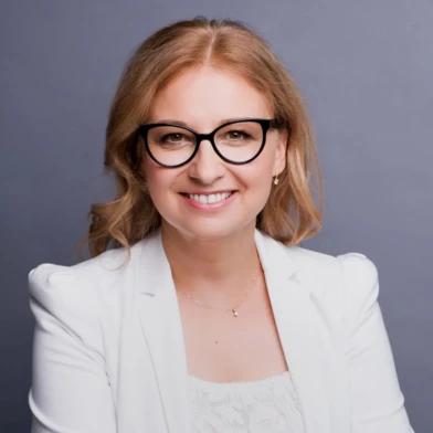 Людина з яскравою посмішкою, яка носить стильні окуляри. У неї доглянуте волосся і щасливий вираз обличчя. Бездоганний догляд за зором.