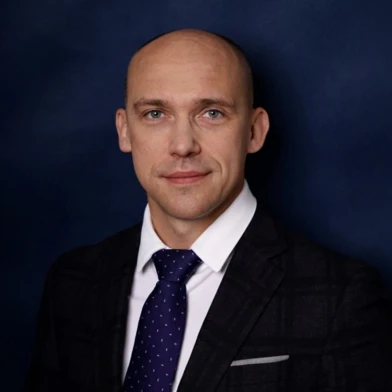 A man wearing a navy blue blazer and white collar shirt, showing his chin, eyebrow, and forehead. The formal wear emphasizes his jaw, shoulder, and neck.