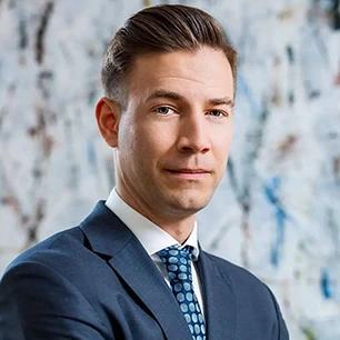 Mężczyzna w eleganckim ubraniu z uniesioną brwią i wydatną szczęką, trzymający rękaw i przypatrujący się w oddali.