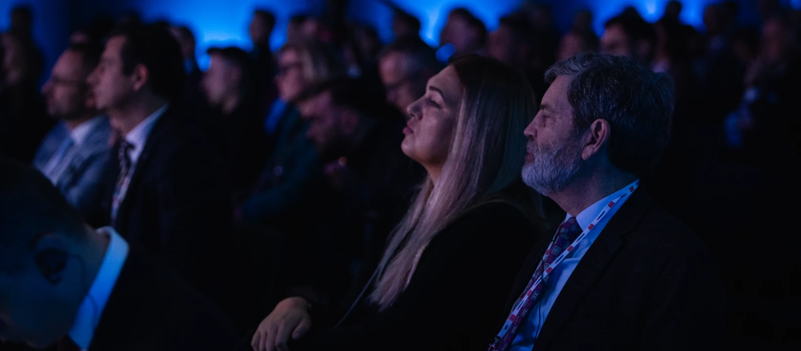 Zróżnicowana grupa ludzi w eleganckich ubraniach biorąca udział w wydarzeniu. Współdziałają z publicznością, nosząc płaszcze i garnitury. Profesjonalna grupa pracowników biurowych.