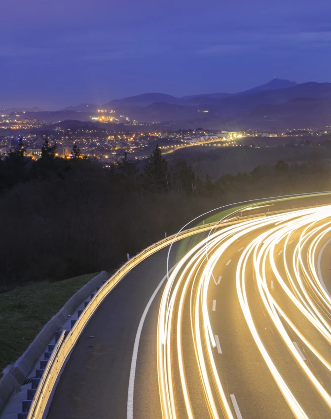 Żółta autostrada ciągnąca się aż po horyzont z wieloma pasami ruchu i słupami elektrycznymi. Droga o ograniczonym dostępie dla użyteczności publicznej.