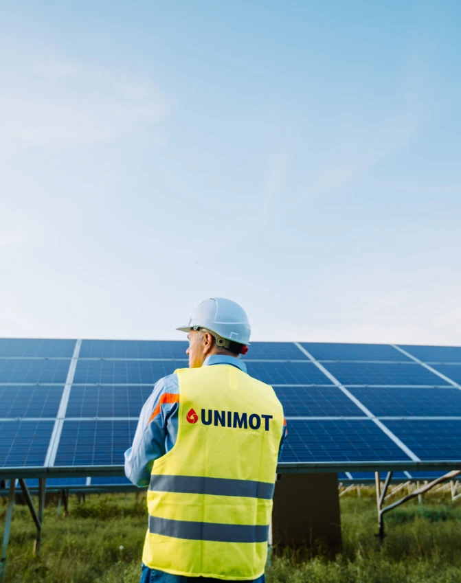 Inżynier, noszący odzież roboczą z wysoką widocznością i kask na placu budowy, promuje bezpieczeństwo i czystość. UNIMOT promuje energię słoneczną dla pracowników fizycznych w branży rzemieślniczej.