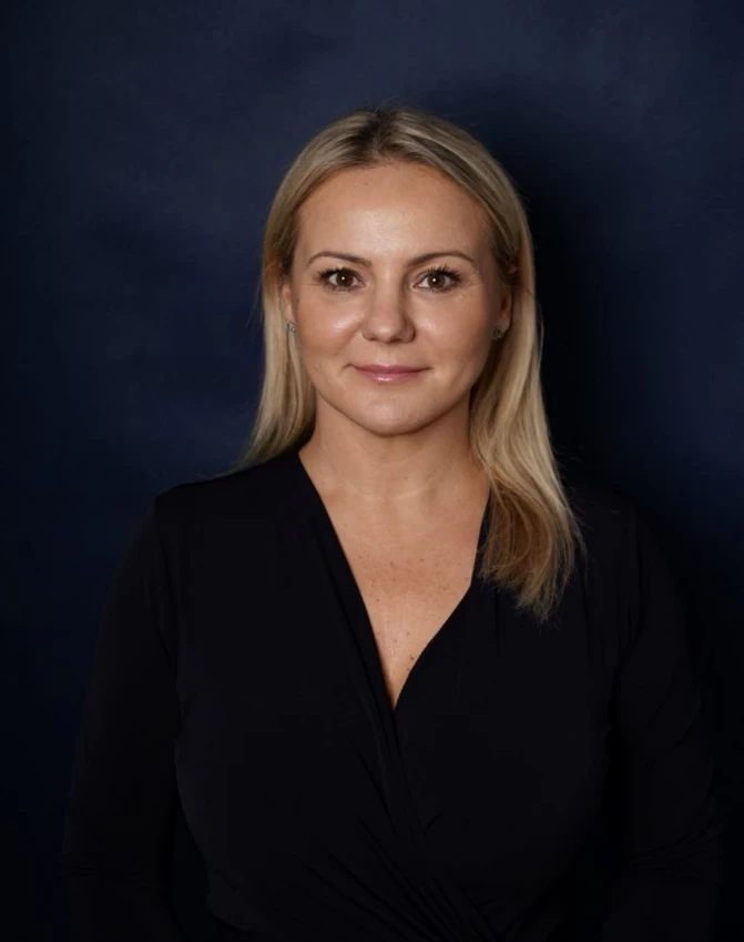 A smiling woman with perfectly groomed eyebrows and lips, glowing skin, and a radiant smile. Her beauty shines through in her joyful facial expression and relaxed posture.