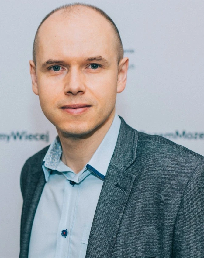 A man in a formal blazer and dress shirt with a serious facial expression, hand on collar, and forehead resting on sleeve, symbolizing determination and focus. Polish text: "Mozemy Wiecej" translates to "We can do more."