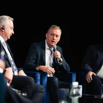 Grupa ludzi w eleganckich garniturach i płaszczach, współdziałających na wydarzeniu.