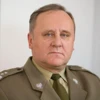 A military officer in formal wear, complete with a crisp white collar and wrinkles on their forehead, stands proudly. This image captures the professionalism and authority of the military person.